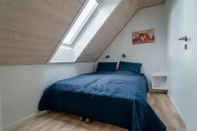 a bedroom with a blue bed in a attic at Hedelandets Camping in Sevel