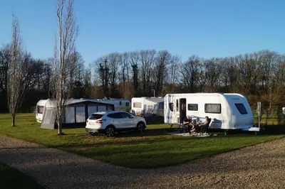 a group of people sitting in front of a parked trailer at Hedelandets Camping in Sevel