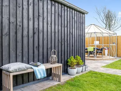 a wooden fence with a bench in a yard at Holiday Home Sulo - 300m from the sea by Interhome in Blokhus