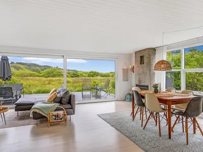 a living room with a couch and a table and chairs at Holiday Home Mintha - 400m from the sea by Interhome in Blokhus