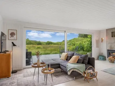 a living room with a couch and a large window at Holiday Home Mintha - 400m from the sea by Interhome in Blokhus