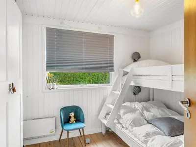 a bedroom with a bunk bed and a blue chair at Holiday Home Mintha - 400m from the sea by Interhome in Blokhus