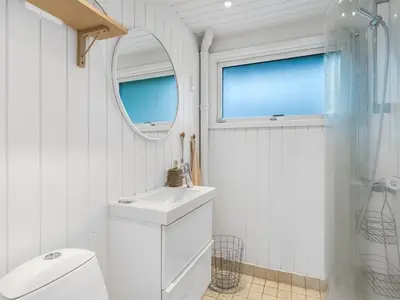 a white bathroom with a sink and a mirror at Holiday Home Mintha - 400m from the sea by Interhome in Blokhus