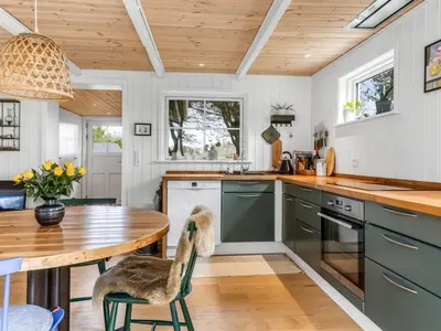 a kitchen with green cabinets and a wooden table at Holiday Home Jenvold - 1-5km from the sea by Interhome in Blokhus