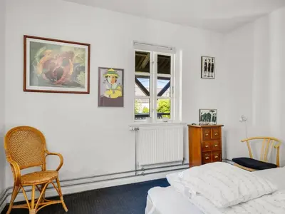 a bedroom with a bed and a chair and a window at Holiday Home Ejnarine - 600m to the fjord by Interhome in Farsø