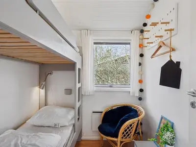 a small bedroom with a bunk bed and a chair at Holiday Home Hermand - 3-5km from the sea by Interhome in Brovst