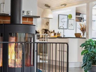 a fireplace in a living room next to a kitchen at Holiday Home Hermand - 3-5km from the sea by Interhome in Brovst