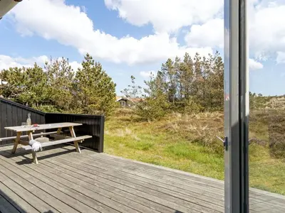 a wooden deck with a picnic table and a window at Holiday Home Elisenda - 1km from the sea by Interhome in Torsted