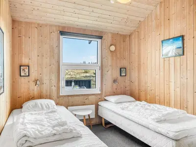 two beds in a room with wooden walls and a window at Holiday Home Elisenda - 1km from the sea by Interhome in Torsted