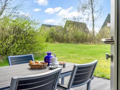 a table with a bowl of fruit and a blue vase on it at Holiday Home Erly - 18km to the fjord by Interhome in Farsø