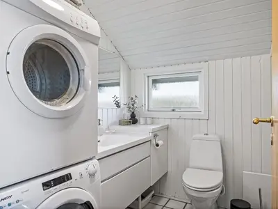 a bathroom with a toilet and a washing machine at Holiday Home Emppu - 250m from the sea by Interhome in Harboør