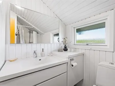 a white bathroom with a sink and a mirror at Holiday Home Emppu - 250m from the sea by Interhome in Harboør
