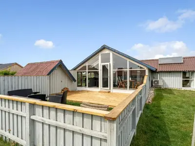 a house with a large deck with a fence at Holiday Home Emppu - 250m from the sea by Interhome in Harboør