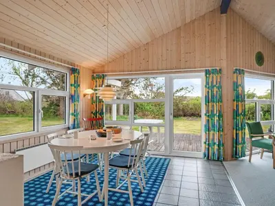 a dining room with a table and chairs and windows at Holiday Home Sella - 200m from the sea by Interhome in Torsted