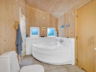 a large white tub in a bathroom with wooden walls at Holiday Home Sella - 200m from the sea by Interhome in Torsted