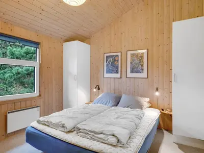 a bedroom with a large bed in a wooden wall at Holiday Home Sella - 200m from the sea by Interhome in Torsted