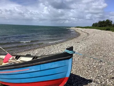 a blue and red boat sitting on a rocky beach at 8 person holiday home in Hurup Thy-By Traum in Sindrup