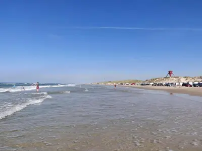 a group of people walking on the beach at 4 star holiday home in Blokhus-By Traum in Blokhus