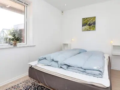 a bed in a white room with a window at 4 star holiday home in Blokhus-By Traum in Blokhus