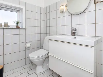 a white bathroom with a toilet and a mirror at 4 star holiday home in Blokhus-By Traum in Blokhus