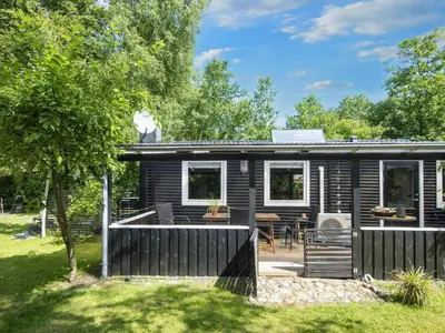 a log cabin with a porch and a patio at 5 person holiday home in Thyholm-By Traum in Thyholm