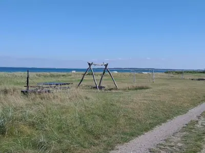 a swing set in a field next to a dirt road at 5 person holiday home in Thyholm-By Traum in Thyholm