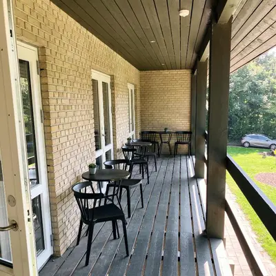 a porch with tables and chairs on a building at Skovly in Viborg