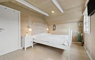 a bedroom with a white bed and a wooden wall at 2 Bedroom Beautiful Home In Farsø in Farsø