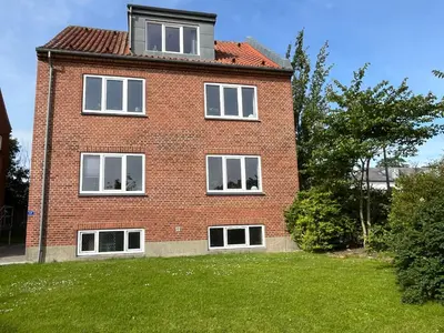 a red brick house with white windows and a yard at Thisted Centrum in Thisted