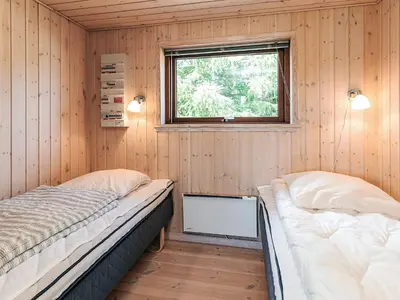two beds in a room with wooden walls and a window at 4 star holiday home in Øster Assels-By Traum in Øster Assels