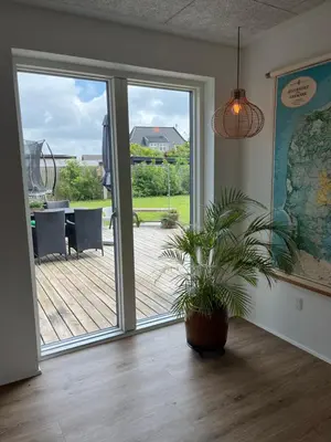 a room with a potted plant in front of a sliding glass door at Hus tæt ved havn og strand in Thyborøn