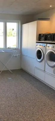 a laundry room with a washing machine and a window at Hus tæt ved havn og strand in Thyborøn