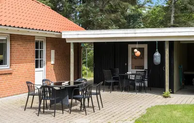 a patio with tables and chairs on a house at 4 Bedroom Beach Front Home In Thyholm in Thyholm