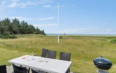 a white table with chairs and a grill on a field at 4 Bedroom Beach Front Home In Thyholm in Thyholm