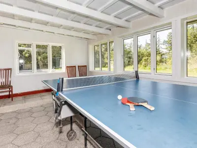 a blue ping pong table in a room with windows at 4 star holiday home in Gedsted-By Traum in Gedsted