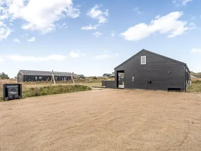 a black house on the side of a dirt road at Holiday Home Dreng - 300m from the sea by Interhome in Harboør