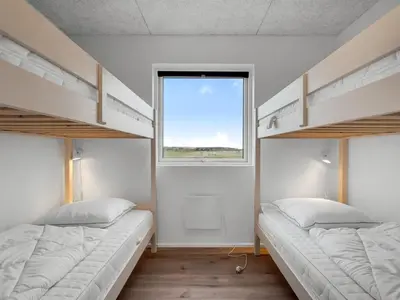 two bunk beds in a room with a window at Holiday Home Dreng - 300m from the sea by Interhome in Harboør