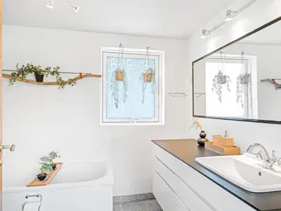a white bathroom with a sink and a mirror at Holiday Home Cillvur - 8km from the sea by Interhome in Thisted