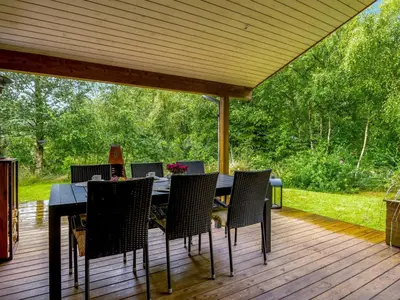 a wooden deck with a table and chairs on it at Holiday Home Zölestine - from the sea by Interhome in Fjerritslev