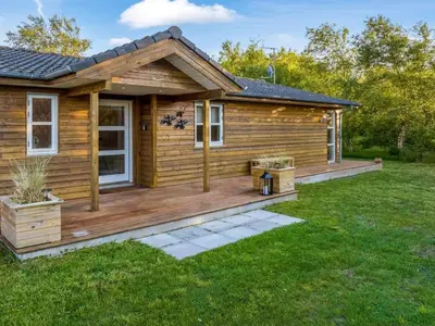 a log cabin with a deck in the yard at Holiday Home Zölestine - from the sea by Interhome in Fjerritslev