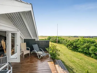 a porch of a house with a chair on a deck at Holiday Home Angelie - 400m from the sea by Interhome in Harboør