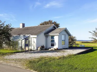 a small white house with a dog in front of it at Light-filled Retreat in Boddum - By Traum Ferienwohnungen in Boddum