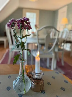 a vase with purple flowers and a candle on a table at Rold Gl Kro in Arden