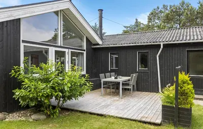 a black house with a wooden deck with a table at 4 Bedroom Lovely Home In Vestervig in Vestervig