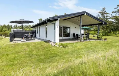 a small white house with a patio and umbrella at Lovely Home In Hurup Thy With Wifi in Sindrup