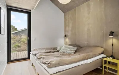 a bed in a room with a large window at 4 Bedroom Pet Friendly Home In Blokhus in Blokhus
