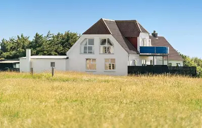 a white house with a brown roof in a field at 4 Bedroom Nice Home In Harboøre in Harboør