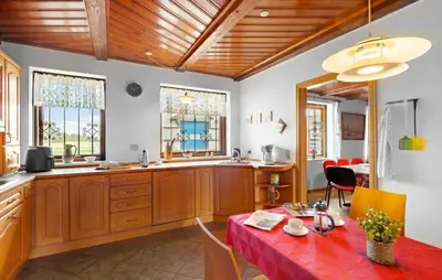 a kitchen with wooden cabinets and a table with a red table cloth at 5 Bedroom Beautiful Home In Brovst in Brovst