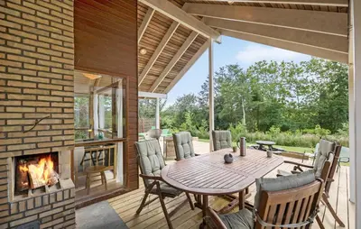 a patio with a wooden table and a fireplace at 3 Bedroom Beautiful Home In Løgstør in Løgstør