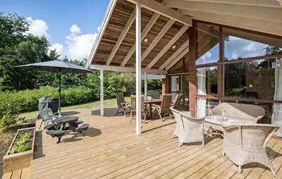 a wooden deck with chairs and an umbrella at 3 Bedroom Beautiful Home In Løgstør in Løgstør